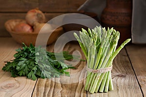 Bunch of fresh green asparagus on a wooden table. Fresh vegetables in a rustic interior.