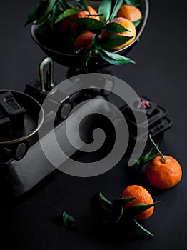 A bunch of fresh juicy clementines with green leaves in a scale