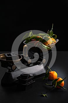 A bunch of fresh juicy clementines with green leaves in a scale