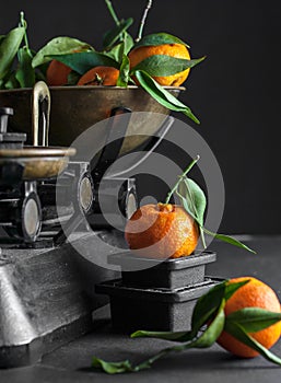 A bunch of fresh juicy clementines with green leaves in a scale