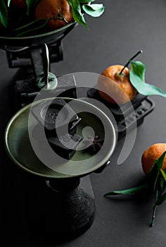 A bunch of fresh juicy clementines with green leaves in a scale