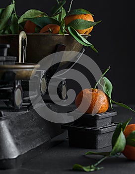 A bunch of fresh juicy clementines with green leaves in a scale