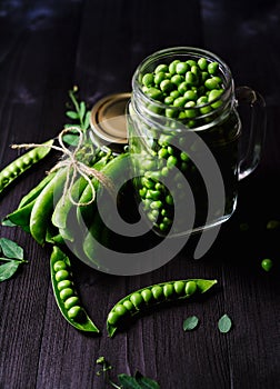 Bunch of fresh mature pods of green peas tied with a rope near.