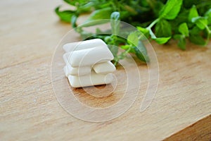 Bunch of fresh mint and gum pads on wooden background