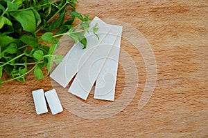 Bunch of fresh mint, lozenges and gum pads on wooden background