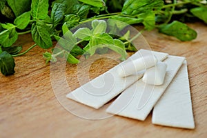 Bunch of fresh mint, lozenges and gum pads on wooden background