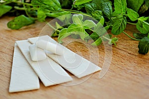 Bunch of fresh mint, lozenges and gum pads on wooden background