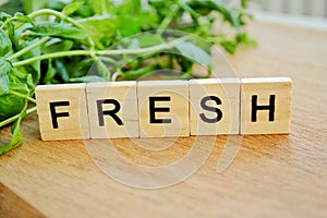 Bunch of fresh mint on wooden background. Word fresh of wooden blocks