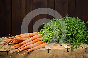 Bunch on fresh orange carrots on wooden box