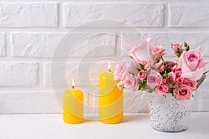 Bunch of fresh pink roses flowers in pot and two yellow candles