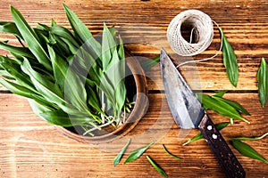 Bunch of fresh ramson with an old knife on wooden textured background.