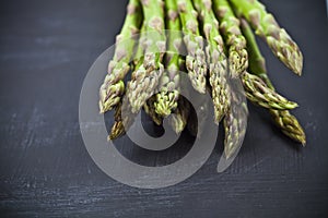 Bunch of fresh raw garden asparagus closeup on black board background. Green spring vegetables