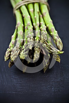 Bunch of fresh raw garden asparagus closeup on black board background. Green spring vegetables