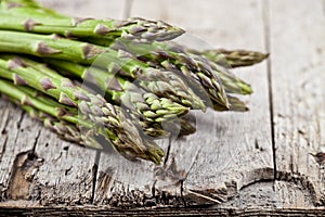 Bunch of fresh raw garden asparagus closeup on rustic wooden table background. Green spring vegetables