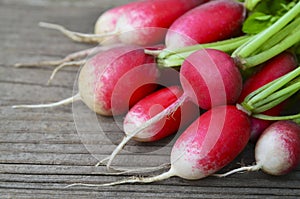 Bunch of fresh raw red radishes on old wooden background.Raphanus sativus.