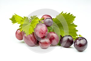 Bunch of fresh pink grapes with green leaves isolated on white background