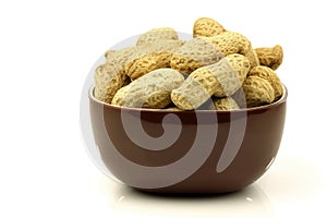 A bunch of fresh roasted peanuts in a brown bowl