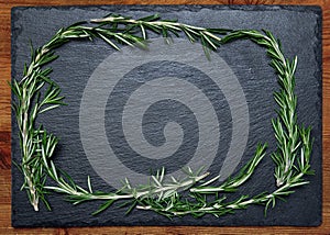 Bunch of fresh rosemary on a black slate, stone or concrete background.