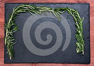 Bunch of fresh rosemary on a black slate, stone or concrete background.