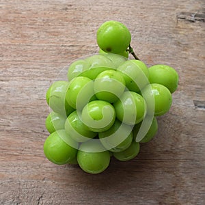 bunch of fresh sweet green shine muscat (vitis vinifera) grape isolate on a wooden background. japanese grapes.