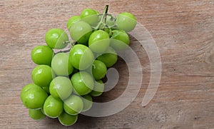 bunch of fresh sweet green shine muscat (vitis vinifera) grape isolate on a wooden background. japanese grapes.