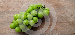 bunch of fresh sweet green shine muscat (vitis vinifera) grape isolate on a wooden background. japanese grapes.