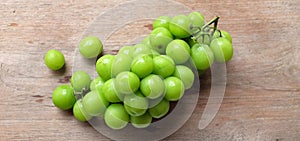 bunch of fresh sweet green shine muscat (vitis vinifera) grape isolate on a wooden background. japanese grapes.