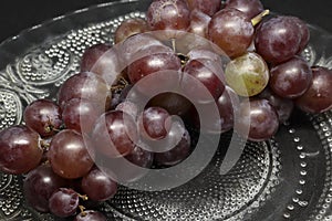 bunch of grapes in a glass plate. on a black background