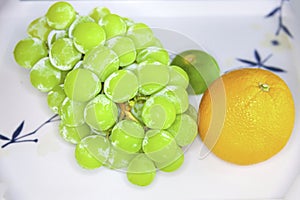 A bunch of grapes and orange in the plate