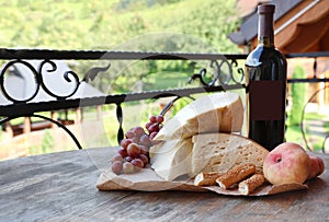 Bunch of grapes, wine, cheese and peaches on wooden table