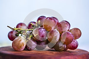 Bunch of grapes on wooden plate isolated on white background