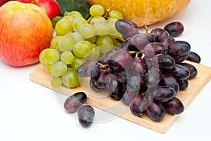 Bunch of Green and Black Grapes Fruits over white on Wooden Board Background