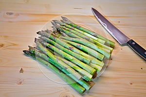Bunch of green fresh asparagus or spargel in german on the choping plate with kitchen knife