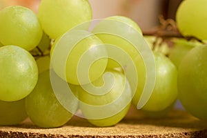 A bunch of green grapes lies on a cork stand. Close-up. Selective focusing