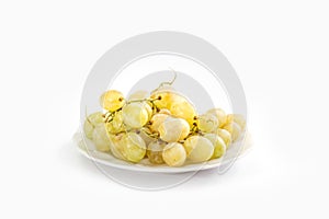 A bunch of green grapes on a plate on a white background