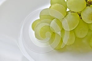 A bunch of green grapes on a white plate