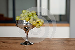 A bunch of green ripe grapes in a metal bowl on a wooden table. Food, healthy eating. Soft selective focus