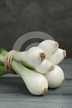 Bunch of green spring onions on grey wooden table, closeup