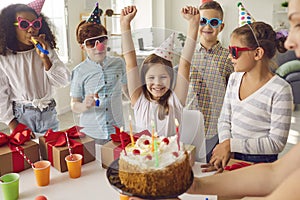Bunch of happy children celebrating their friend`s birthday at fun party at home