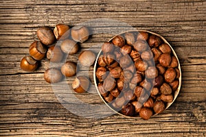Bunch of hazelnut not purified and purified on old wood background.