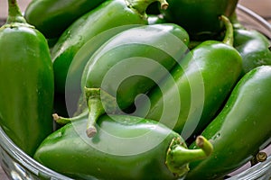 Bunch of JalapeÃ±o peppers on a kitchen counter waiting to be sliced up with a knife by the chef.