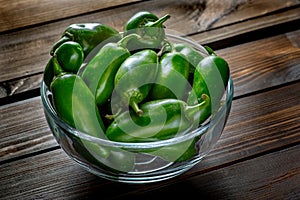 Bunch of JalapeÃ±o peppers on a kitchen counter waiting to be sliced up with a knife by the chef.