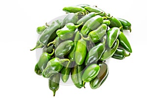 Bunch of JalapeÃ±o peppers on a kitchen counter waiting to be sliced up with a knife by the chef.