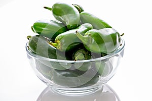 Bunch of JalapeÃ±o peppers on a kitchen counter waiting to be sliced up with a knife by the chef.