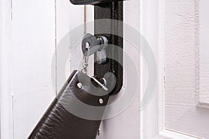 A bunch of keys with a leather key case inserted in a keyhole in order to open or lock a white wooden door, home security and