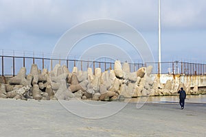 Bunch of large concrete tetrapod breakwaters lie on the seashore near pier