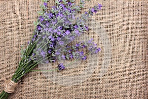 Bunch of lavender flowers on burlap fabric texture.