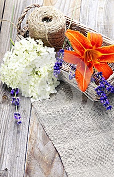 Bunch of lavender flowers and lily in basket on an old wood tab