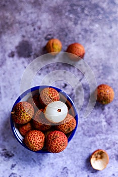 bunch of lychees in a bowl on purple wooden mat