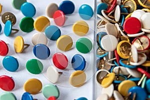 Bunch of many colorful thumbtacks as multi-color office supply metal pushpins circles in yellow, green, blue, red and white desk